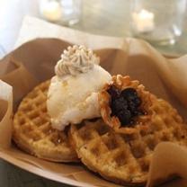 Two brown waffle-ish looking foods on a plate with a dollup of something white and something purple