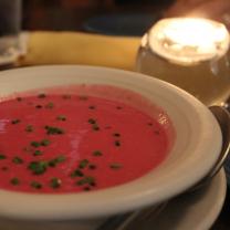 White bowl with red soup and green chives sprinkled on top