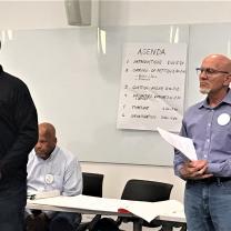 Two men at the front of a room speaking