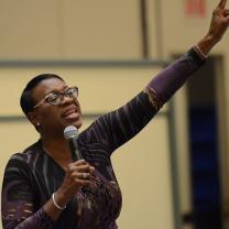 Black woman giving a speech raising her arm in the air