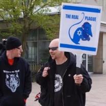 Protester outside Ohio statehouse with sign saying The Real Plague with a rat with a swatiska on it