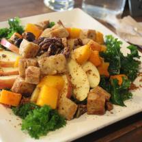 A square white plate filled with vegetables and green garnishes