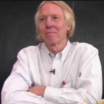 Man in white shirt leaning elbows on table