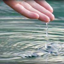 Person's hand above water with drops dripping off