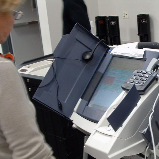 Older woman standing by an electronic voting machine