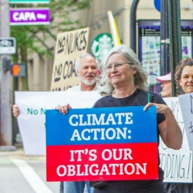 Woman holding a sign saying Climate Action It's our Obligation