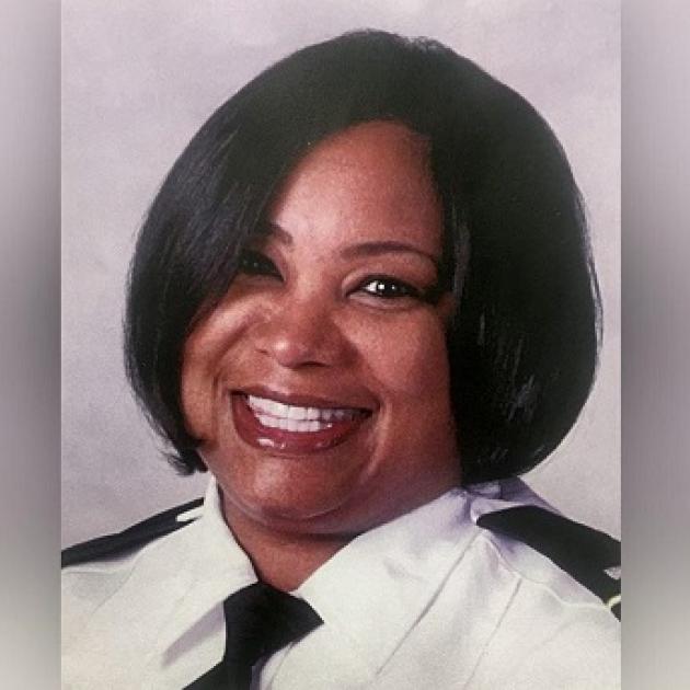 Head shot of black woman with short black hair smiling wearing a police uniform