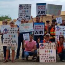 Many people posing outside holding signs about the environment