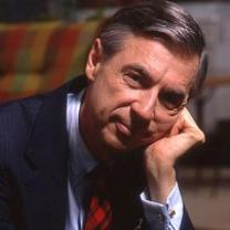 Older white man with dark and gray hair wearing a suit with his head resting on his hand