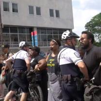 Police al suited up with helmets and bikes attacking stationary black people with black tape over their mouths