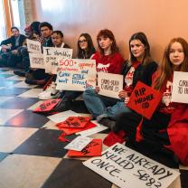 Students with protest signs sitting in a hall