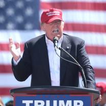 Trump in front of flag with red baseball cap on