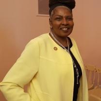 Black woman with updo wearing a yellow suit