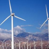 Two large white wind turbines in the foreground and a bunch of them in the distance