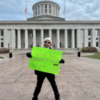 Man holding sign in front of Statehouse