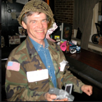 White man with a helmet on a big smile, and a camouflage jacket